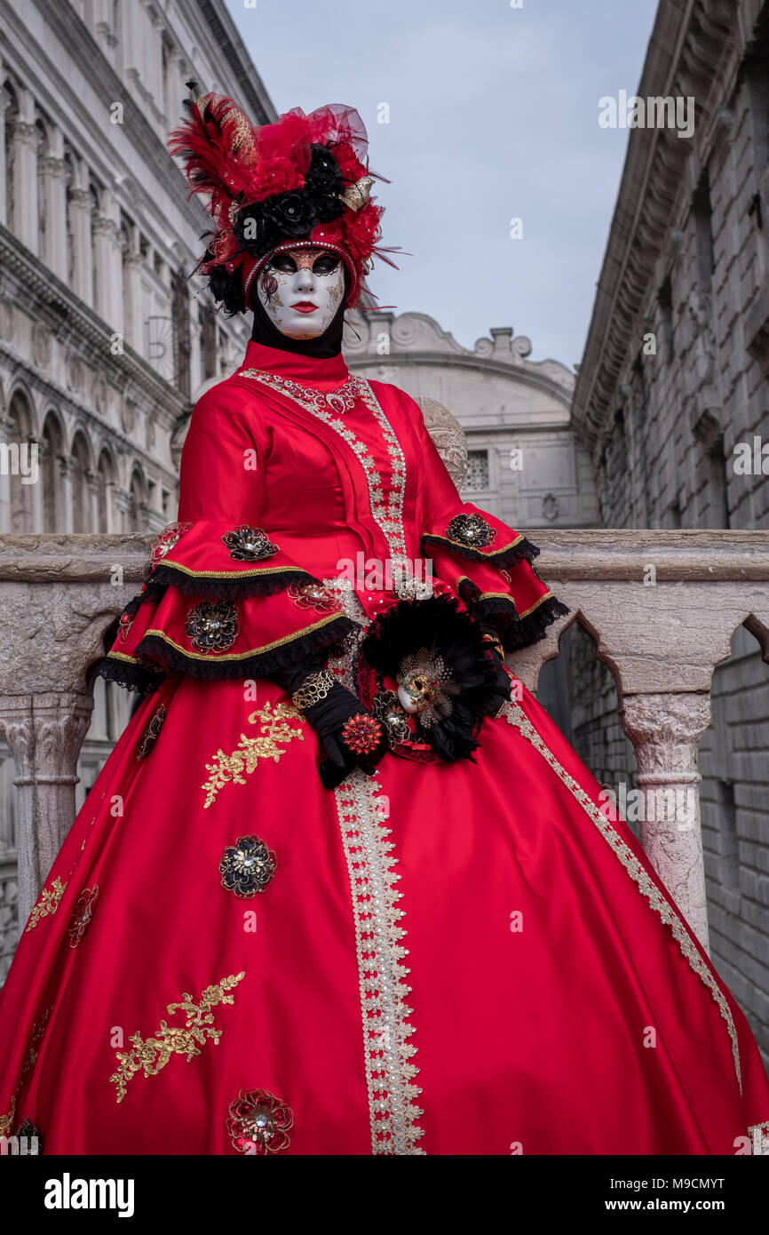 Femme en robe rouge vif et un masque, se tenant sur le Pont des Soupirs  dans l'arrière-plan pendant le carnaval vénitien (Carnaval de Venise Photo  Stock - Alamy