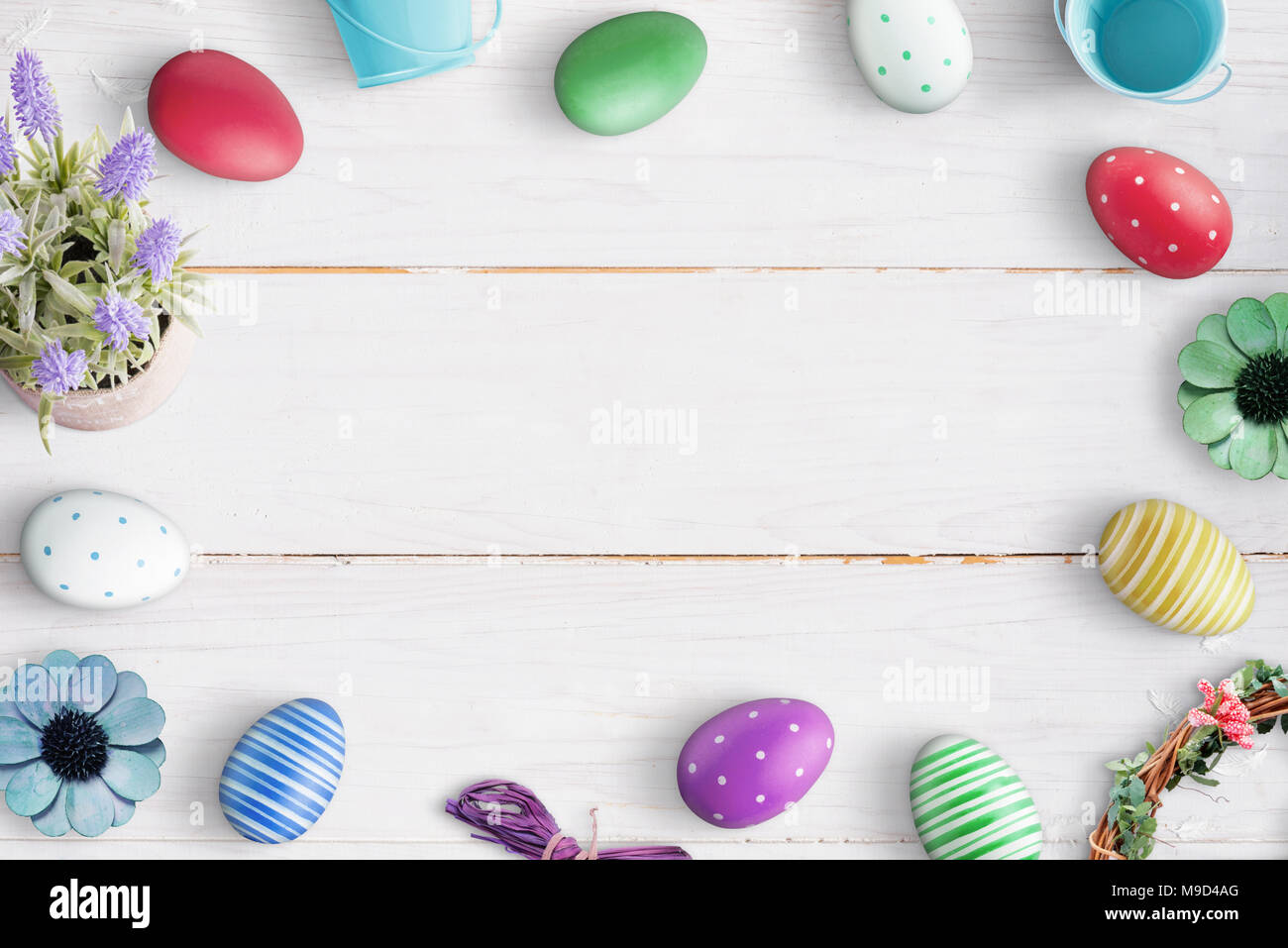 Composition de Pâques avec des oeufs colorés sur fond de bois blanc. Espace libre au milieu pour le texte. Banque D'Images