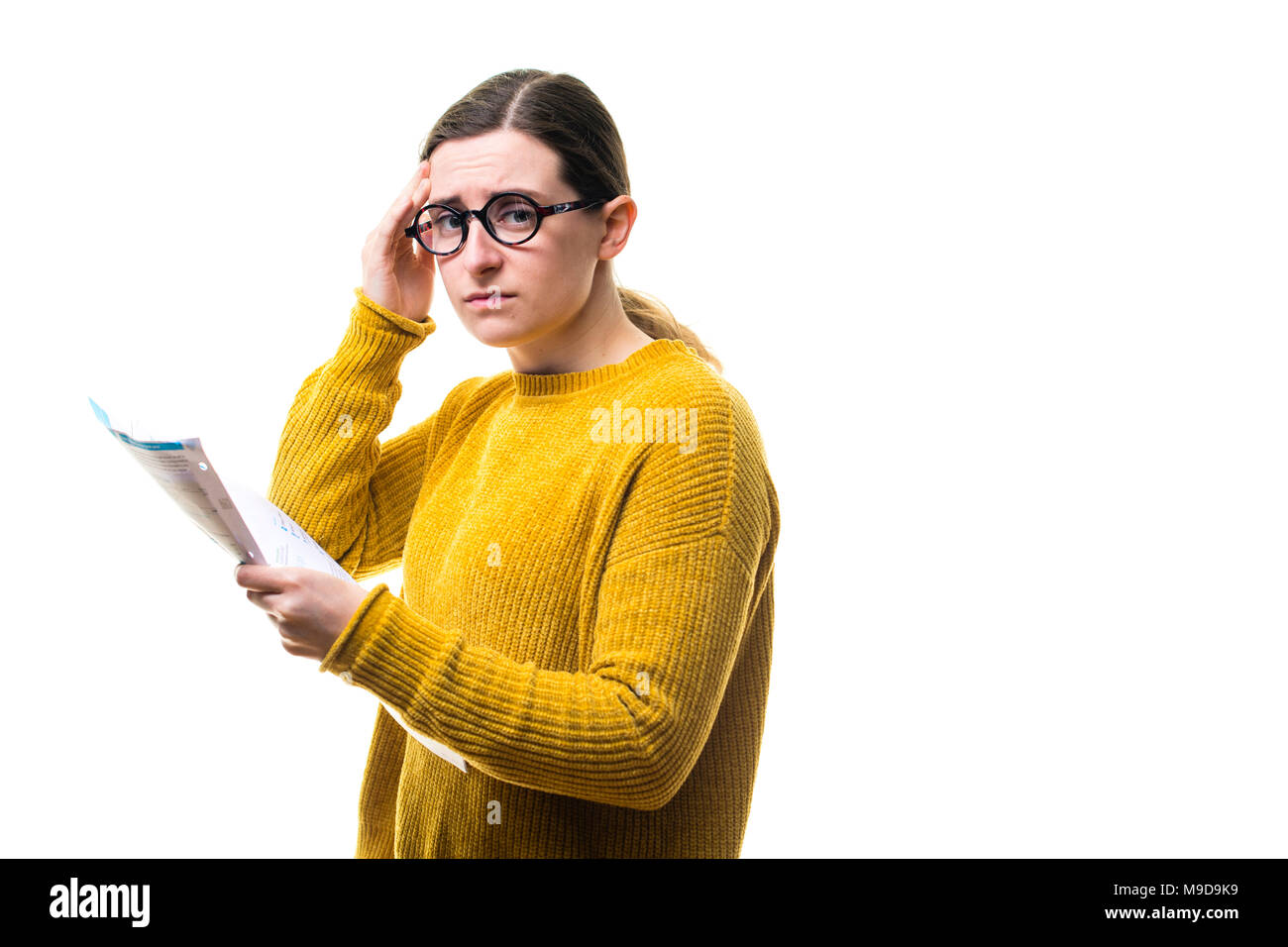 Soucis d'argent et finances personnelles : une jeune femme de race blanche fille portant un chandail de cavalier jaune, regardant ses factures et inquiet au sujet de payer les frais d'accueil de l'utilitaire , Royaume-Uni Banque D'Images