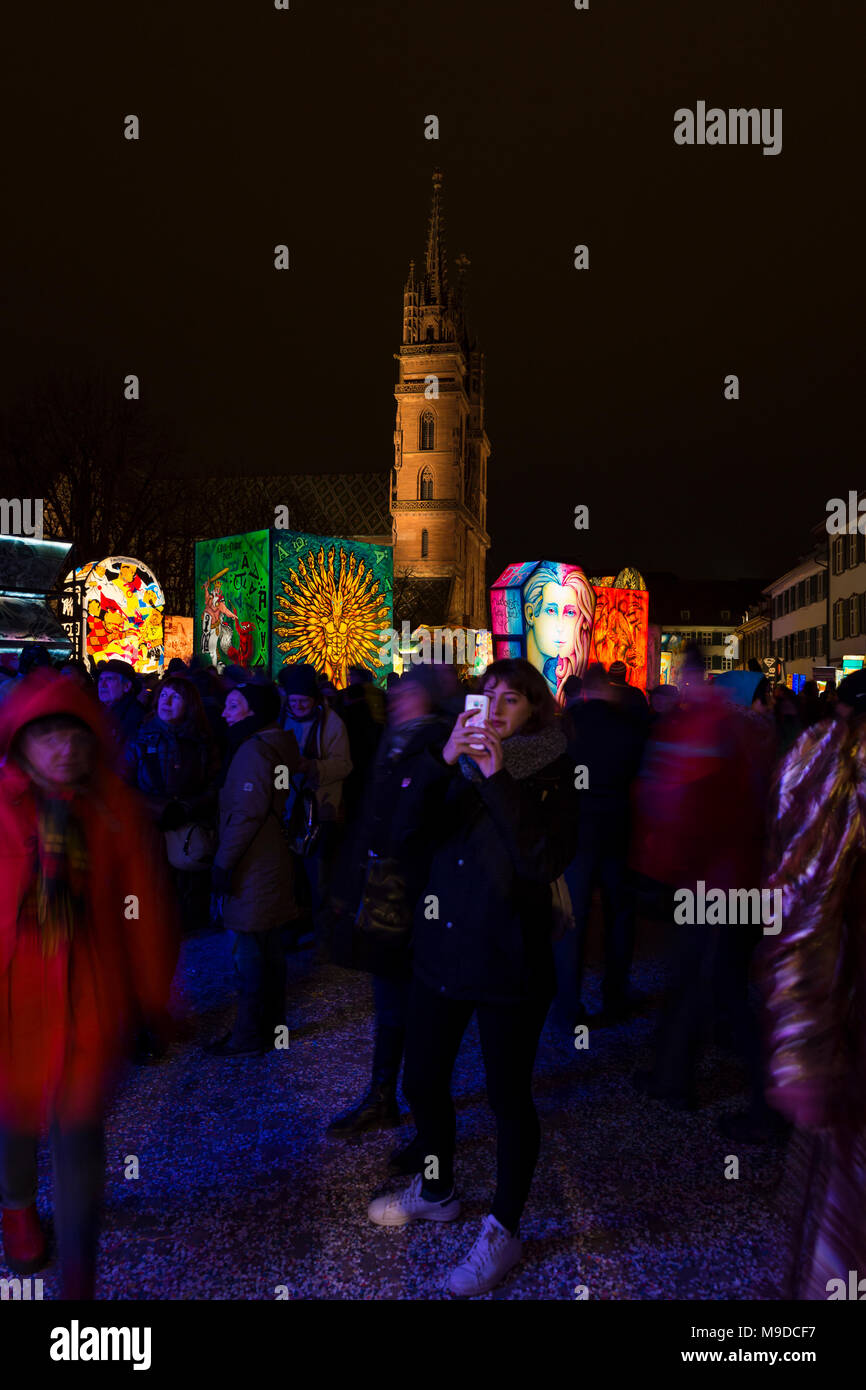 Muensterplatz, Bâle, Suisse - 20 février 2018. Carnaval de Bâle. Une jeune femme à prendre des photos avec son téléphone intelligent. La cathédrale de Bâle avec illumi Banque D'Images