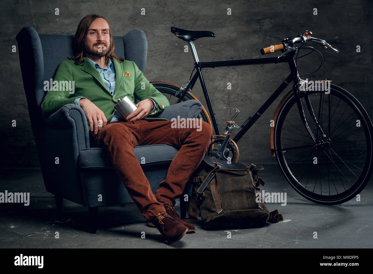 Un homme vêtu d'une veste verte est assis sur une chaise avec un seul spee Banque D'Images