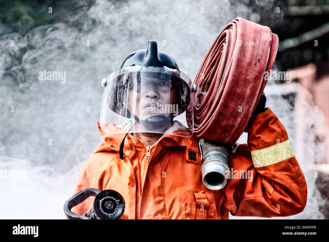 D'Incendie et de sauvetage d'urgence de la formation, les pompiers en uniforme, effectuer un jet d'eau à travers d'une flamme Banque D'Images