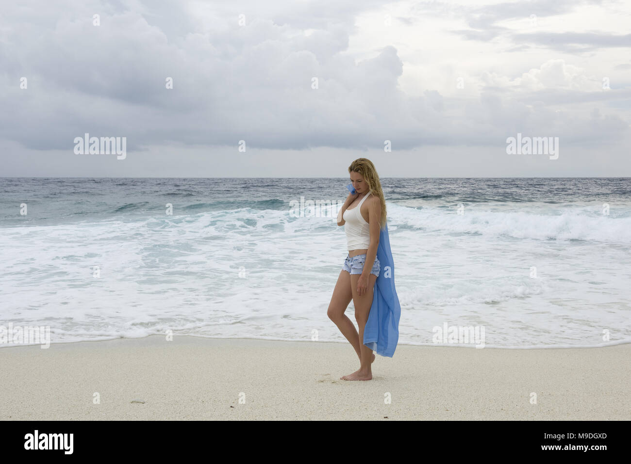 Jeune femme marche le long d'une plage déserte Banque D'Images