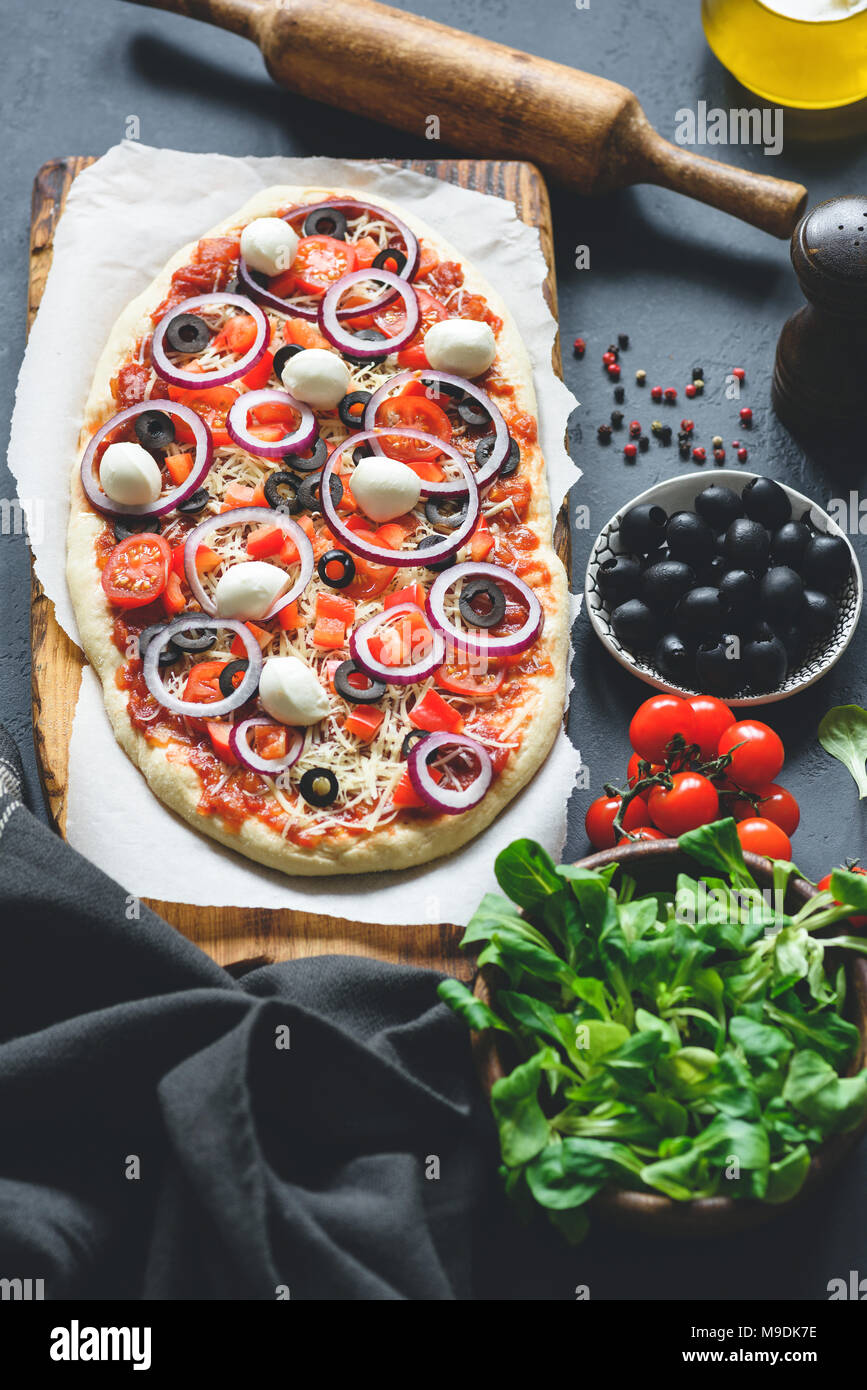 Des pizzas aux olives noires, fromage mozzarella, sauce tomate et oignon rouge. Vertical, vue d'en haut Banque D'Images