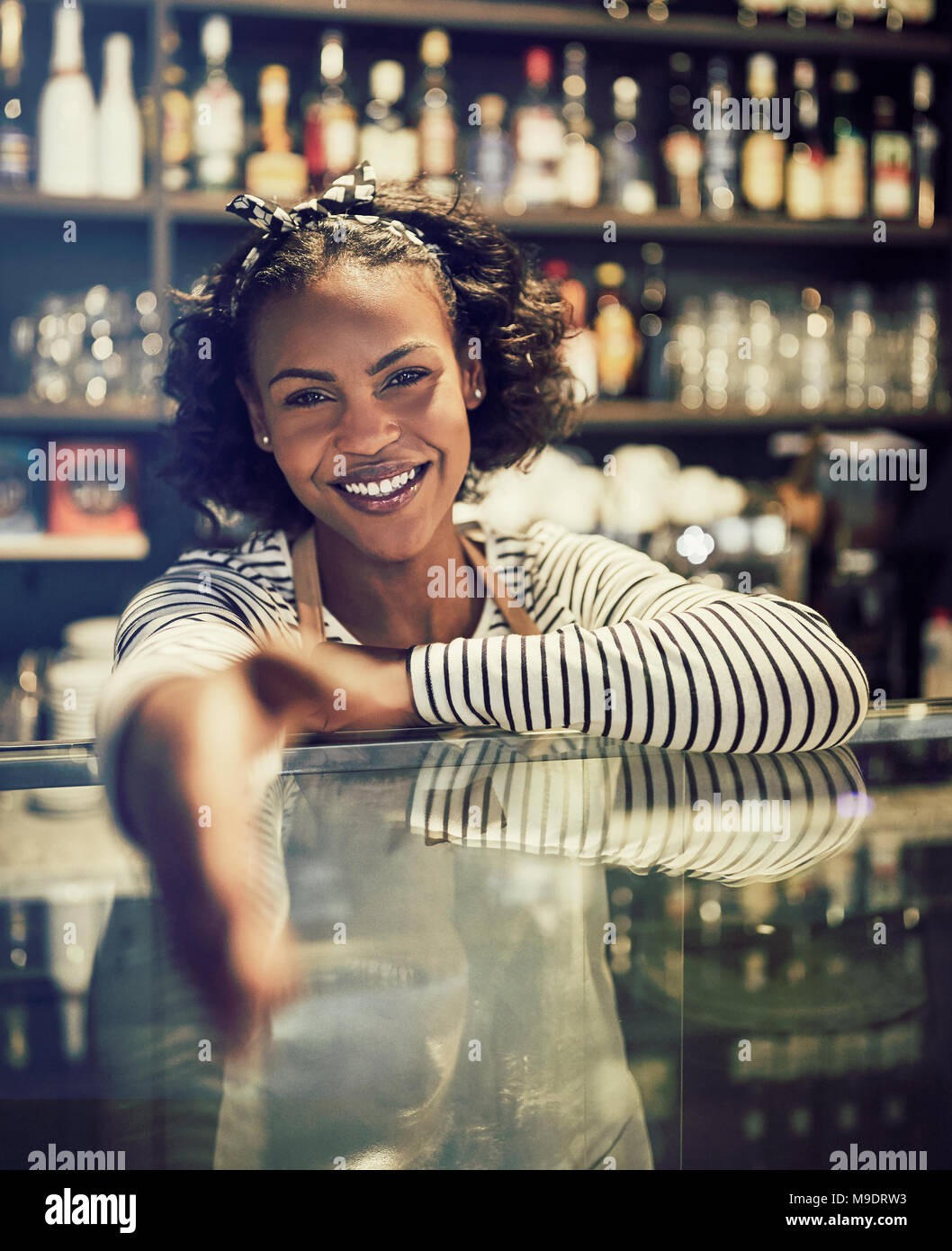 Les jeunes entrepreneurs africains smiling et l'extension d'une poignée de main en se tenant debout derrière le comptoir de son café à la mode Banque D'Images