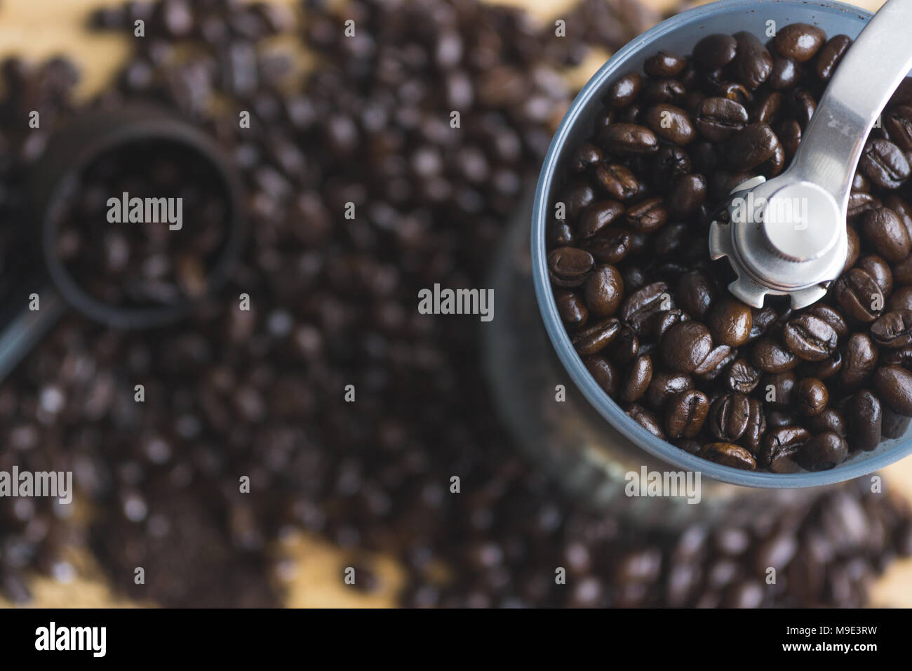 Moulin à café manuel et cuillère de mesure avec les grains de café renversé sur planche de bois. Banque D'Images