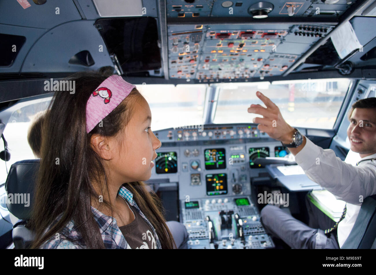Portugal, Algarve, Faro. Vers le 10 juillet 2013. Photo d'une petite fille dans le poste de pilotage d'avion commercial de la compagnie aérienne TAP avec le pilote qui se charge des commandes. Banque D'Images
