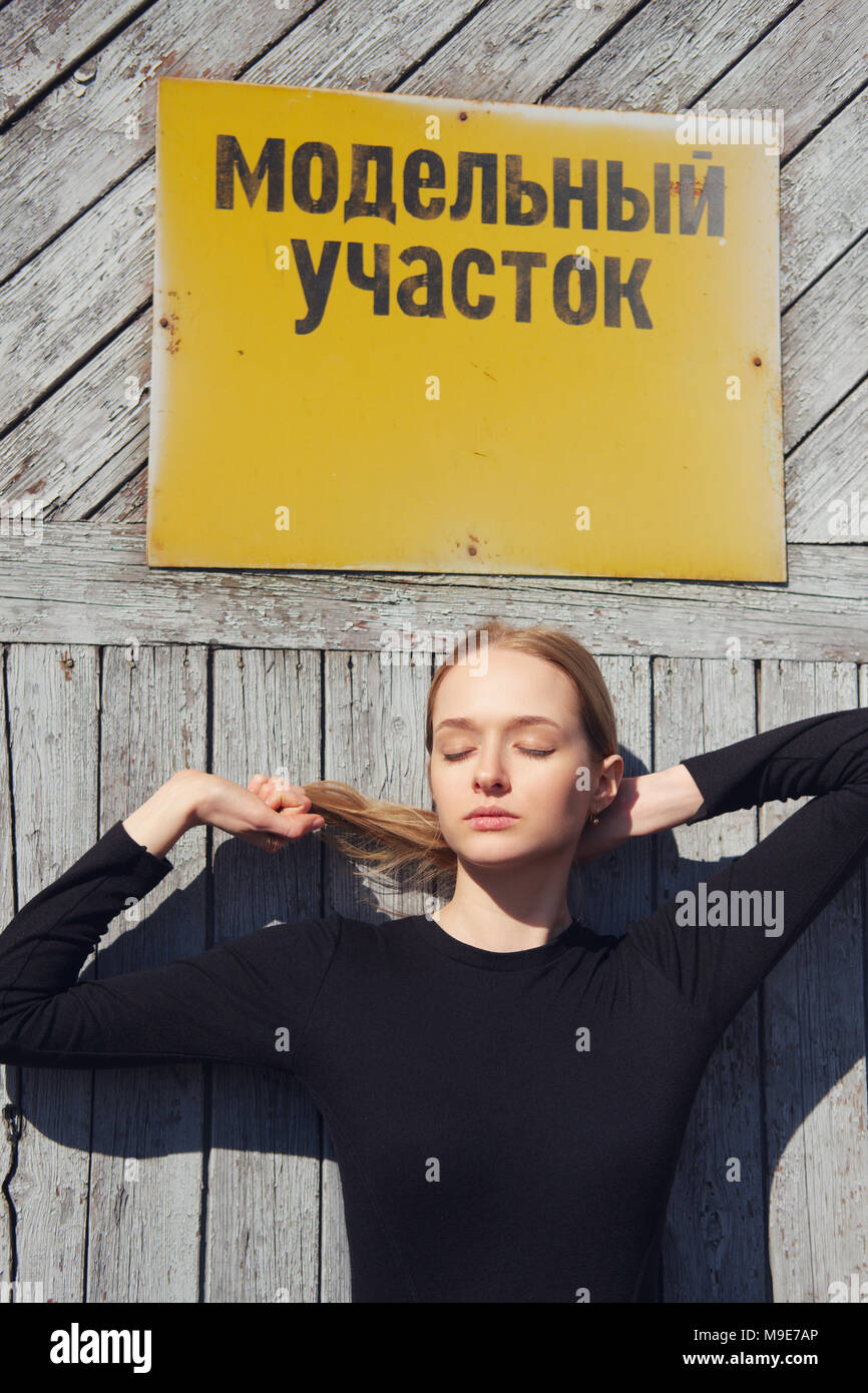 Pretty model posing in front of factory porte avec plaque d'avertissement. (Inscription sur plaque est sur le russe peut être traduit comme région modèle) Banque D'Images