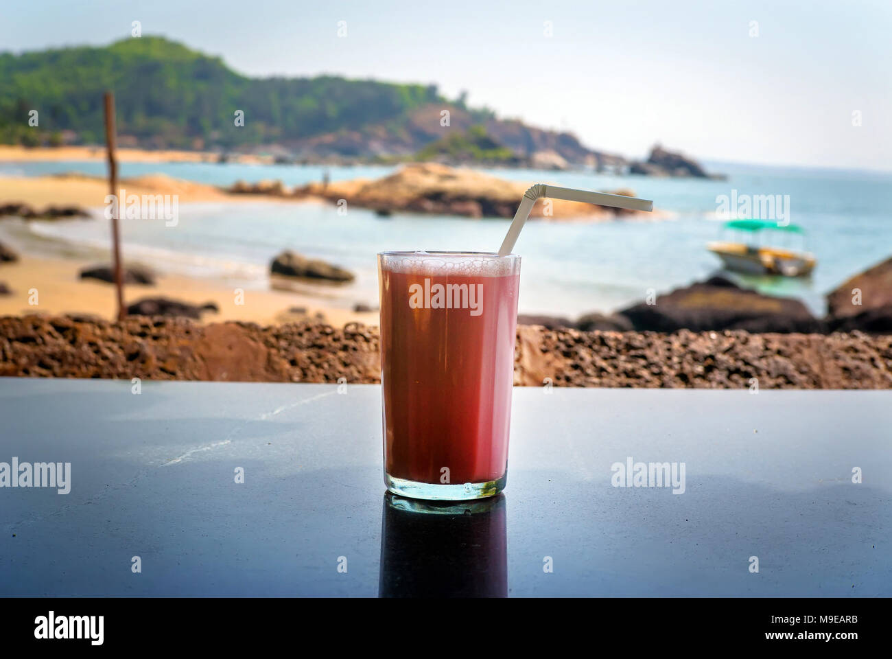 Cocktail aux fraises avec une paille dans un verre se trouve sur le tableau de fond de la mer. Petit déjeuner Banque D'Images