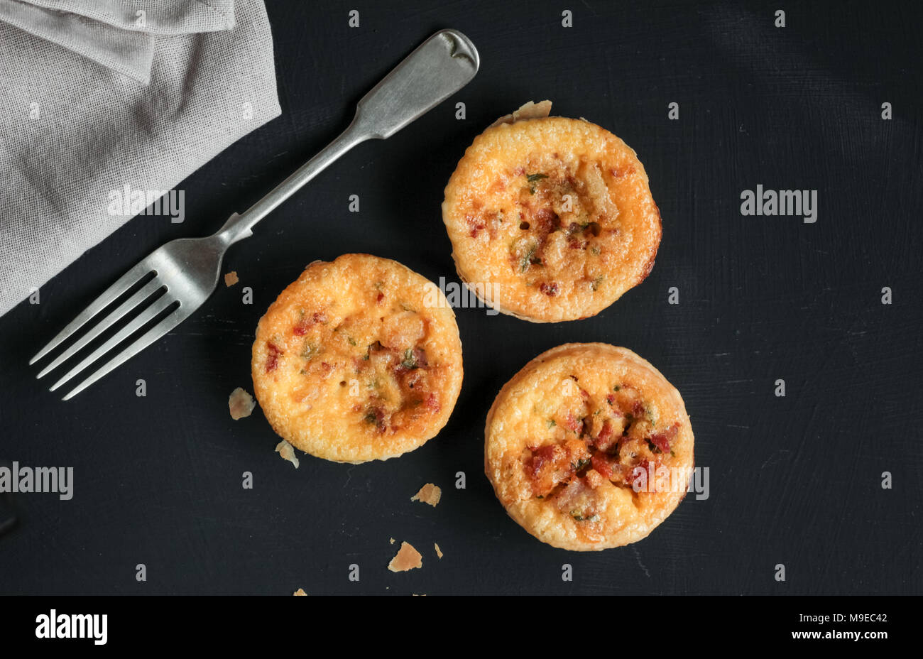 Mini quiches salés sur tableau noir avec une fourchette Banque D'Images