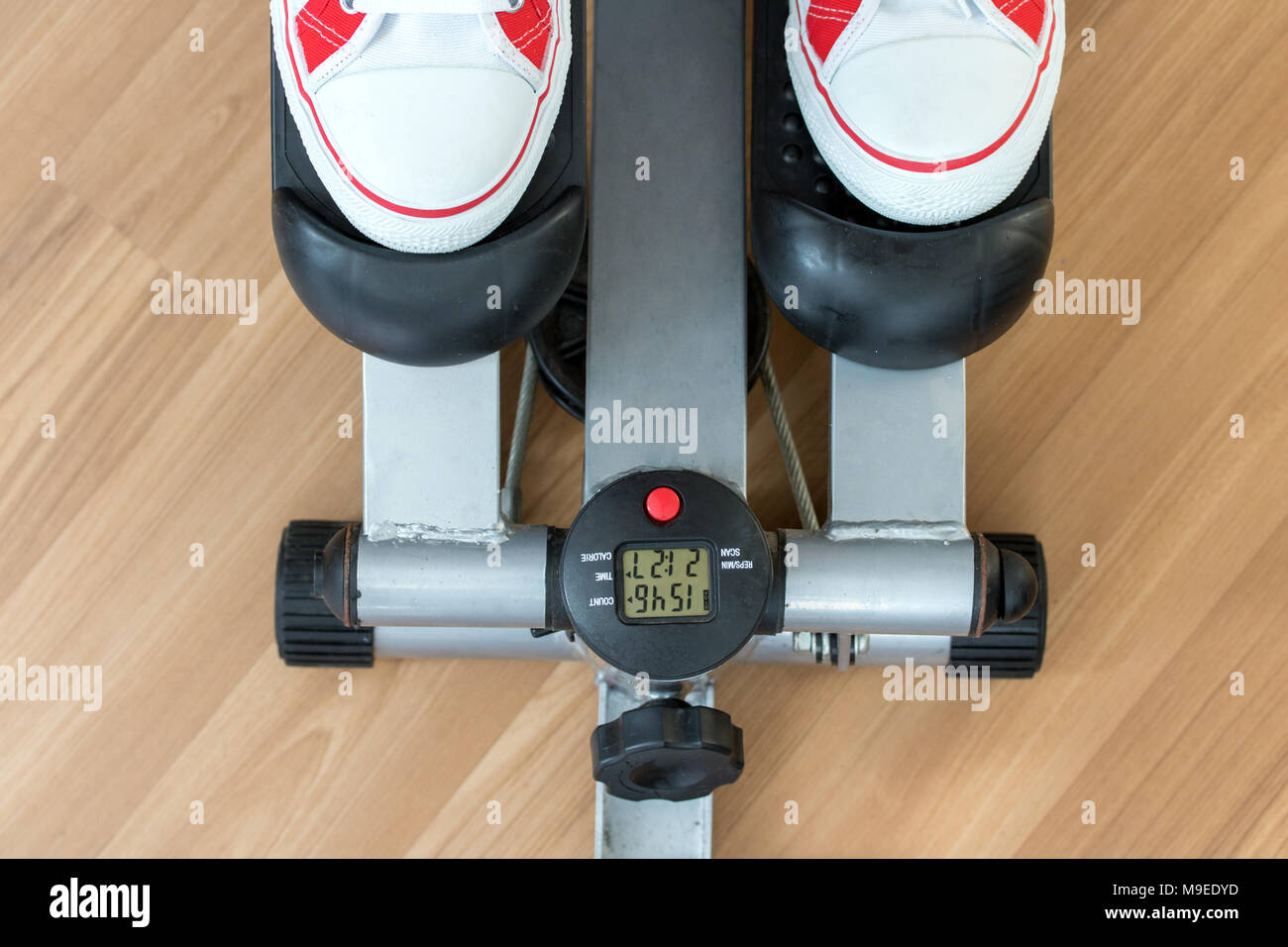 Exercice sur une machine pas à pas, à la recherche d'en haut. Personne active avec les chaussures de sport sur l'exercice de pas-à-pas sur un plancher de bois, Close up. Banque D'Images