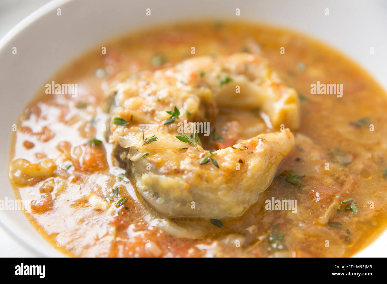 Un simple ragoût de poisson composé de congre escalopes poêlées mijoté dans l'oignon, la tomate, l'ail, le thym, le safran et les stocks de poissons. Dorset England UK GO Banque D'Images