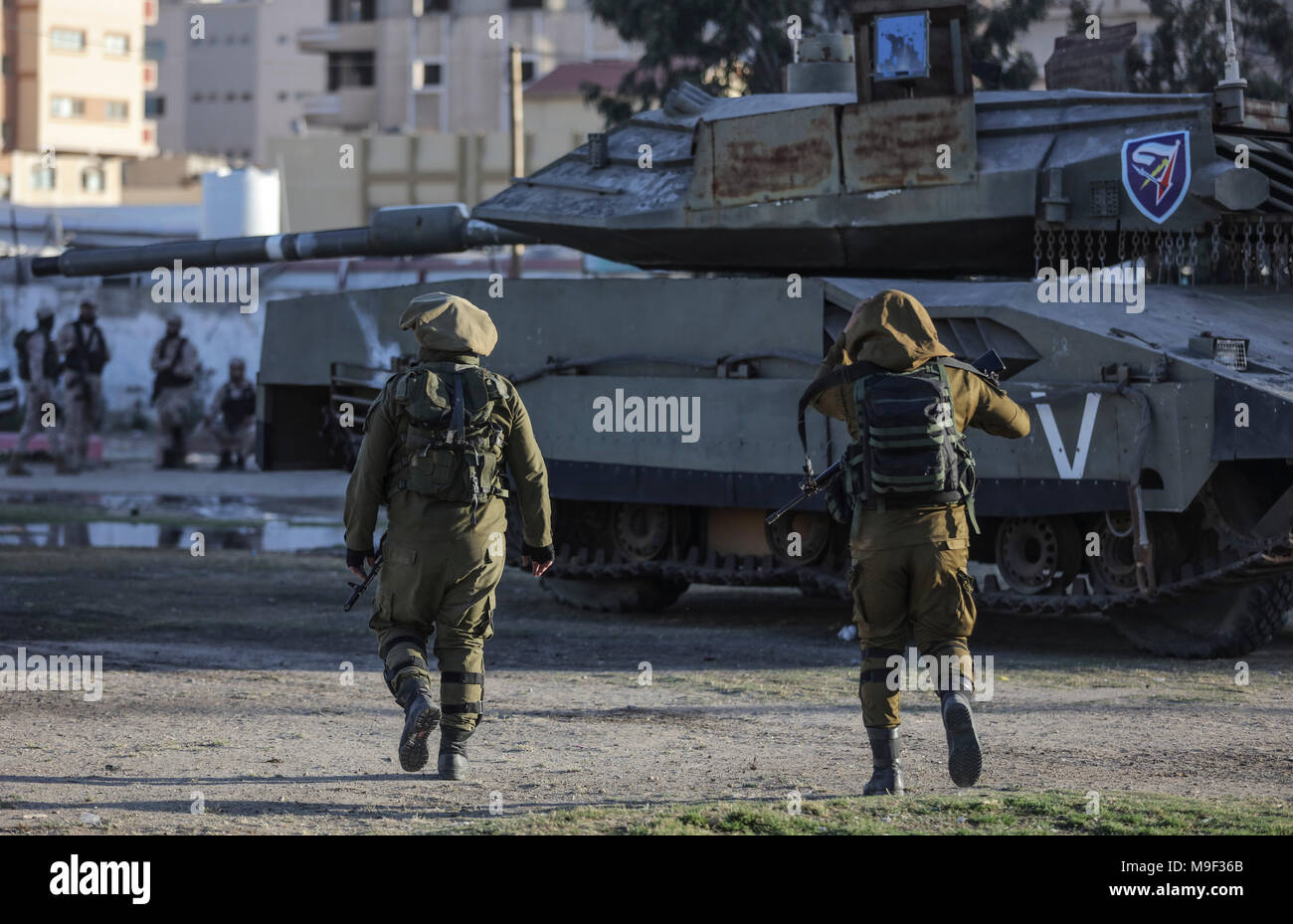 Des militants masqués de Izz ad-Din al-Qassam, la branche militaire du mouvement islamiste palestinien Hamas, passons un modèle grandeur nature d'un Israélien Merkava réservoir pendant un exercice à grande échelle à l'extérieur de la ville de Gaza, bande de Gaza, le 25 mars 2018. Photo : Wissam Nassar/dpa Banque D'Images
