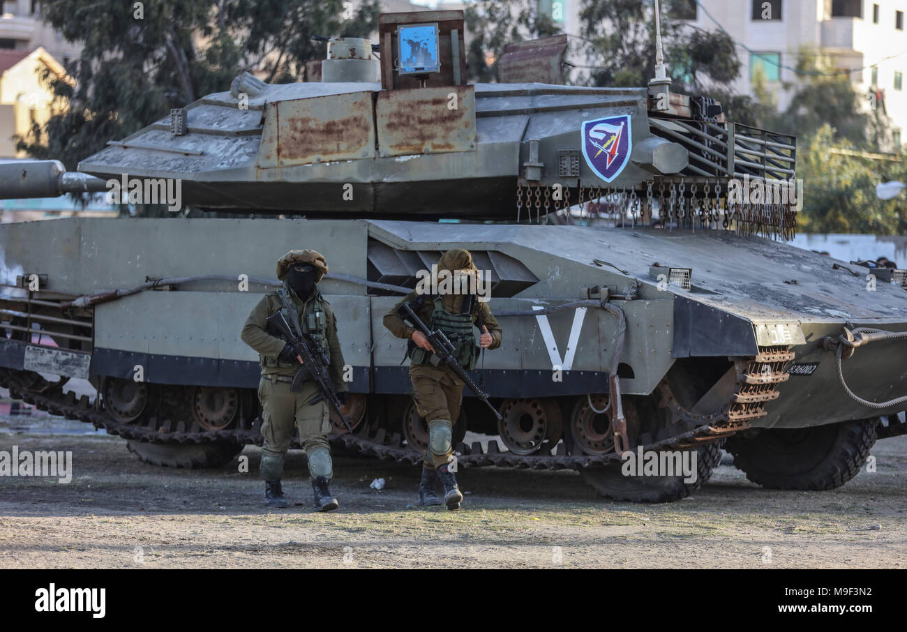Des militants de Izz ad-Din al-Qassam, la branche militaire du mouvement islamiste palestinien Hamas, passons un modèle grandeur nature d'un Israélien Merkava réservoir pendant un exercice à grande échelle à l'extérieur de la ville de Gaza, bande de Gaza, le 25 mars 2018. Photo : Wissam Nassar/dpa Banque D'Images