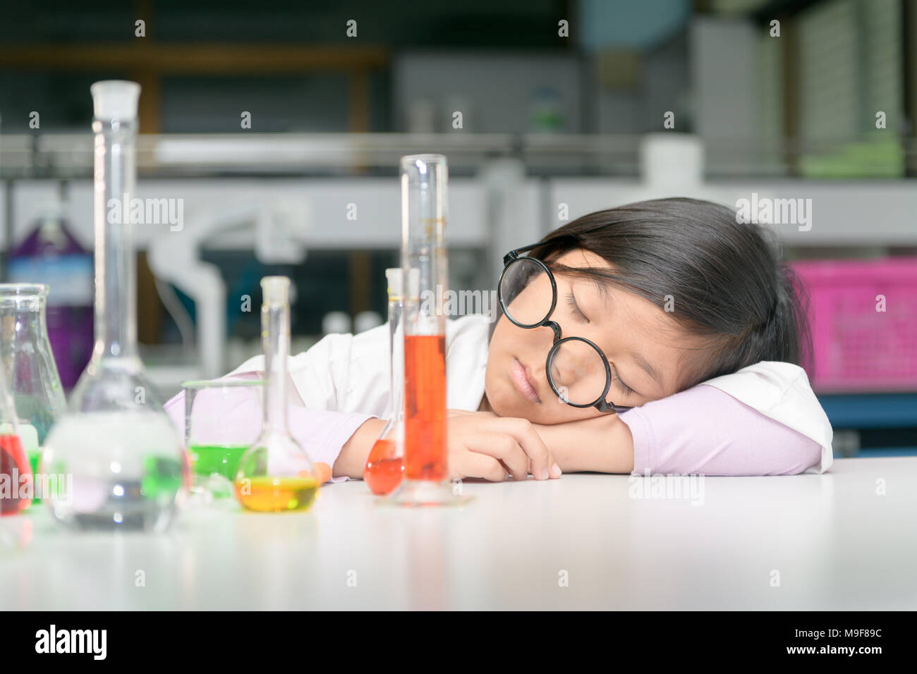 Les étudiants de chimie mignon dormir après avoir fait l'expérience de la science avec de l'équipement et attendre après réaction chimique en laboratoire, mélange de travail scientis Banque D'Images