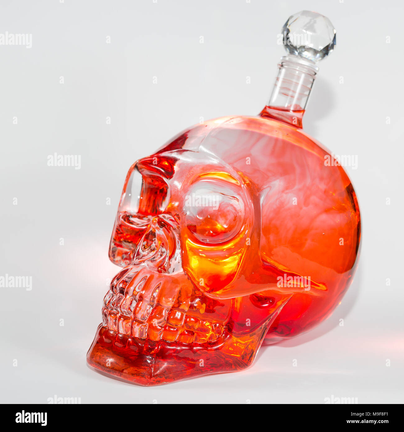 Crâne de verre avec des gouttes d'encre rouge et orange dans l'eau, l'alcool Banque D'Images