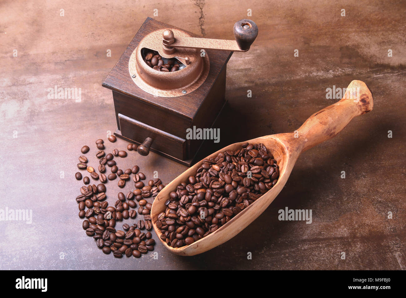 Grains de café dans un moulin à café en bois et scoop sur pierre sombre tableau. Banque D'Images