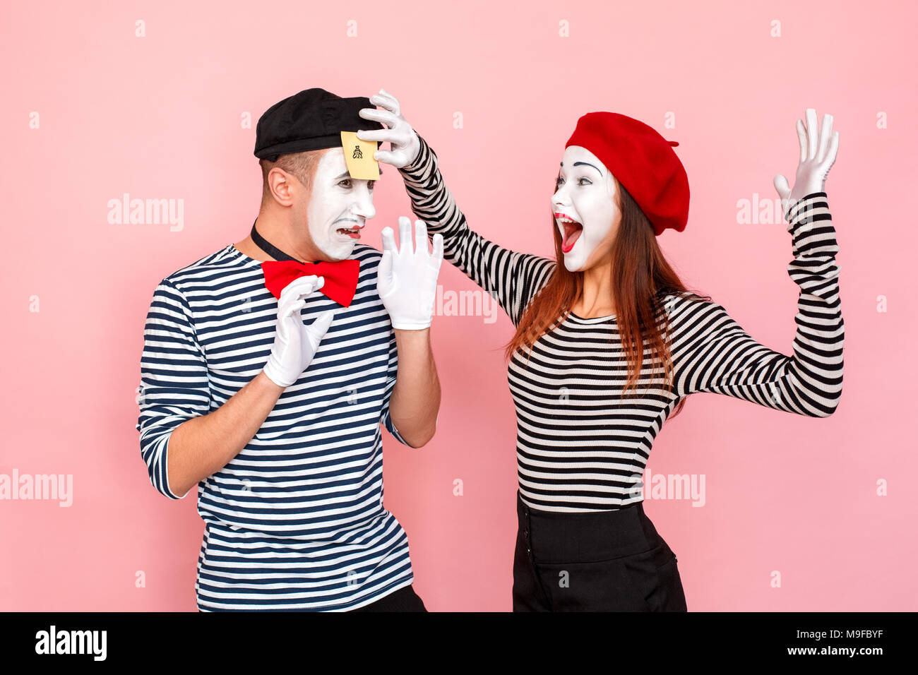 Femme collé le sticker au gars sur le front qu'il est malheureux. Clown, artiste , pantomime . Fond rose, Studio shot Banque D'Images