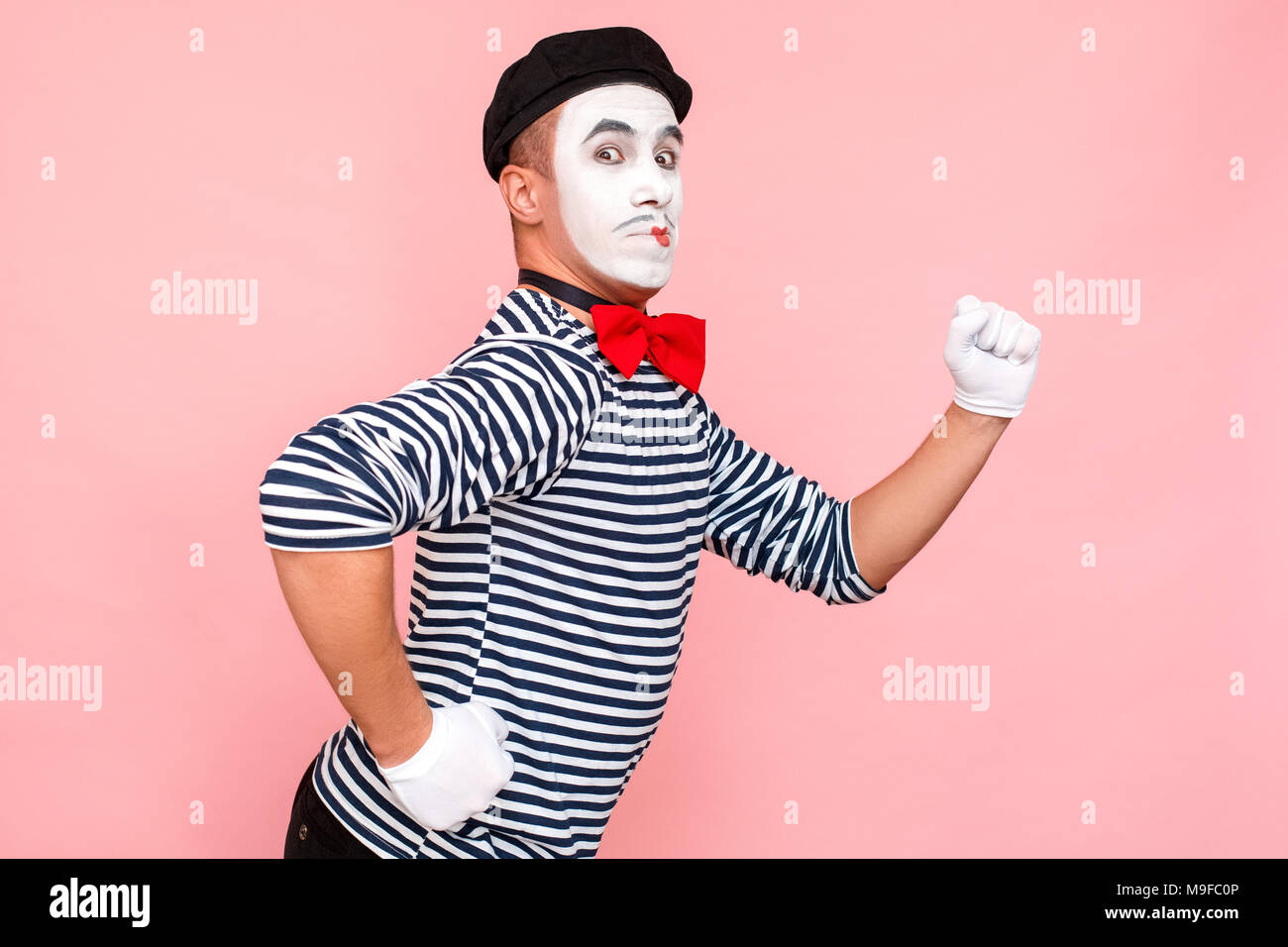 L'homme drôle de marcher et de regarder l'appareil photo. Clown, artiste , mime. Fond rose, Studio shot Banque D'Images