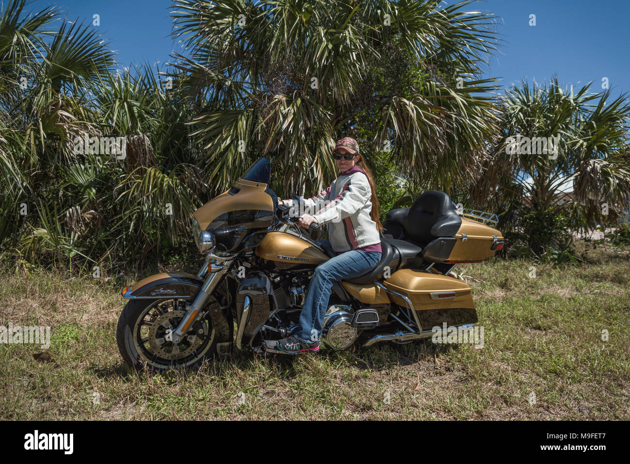 Jolie jeune fille avec de longs cheveux rouges portant des lunettes de soleil et chapeau assis sur une Harley Davidson Ultra Limited 2017 en Floride USA Banque D'Images