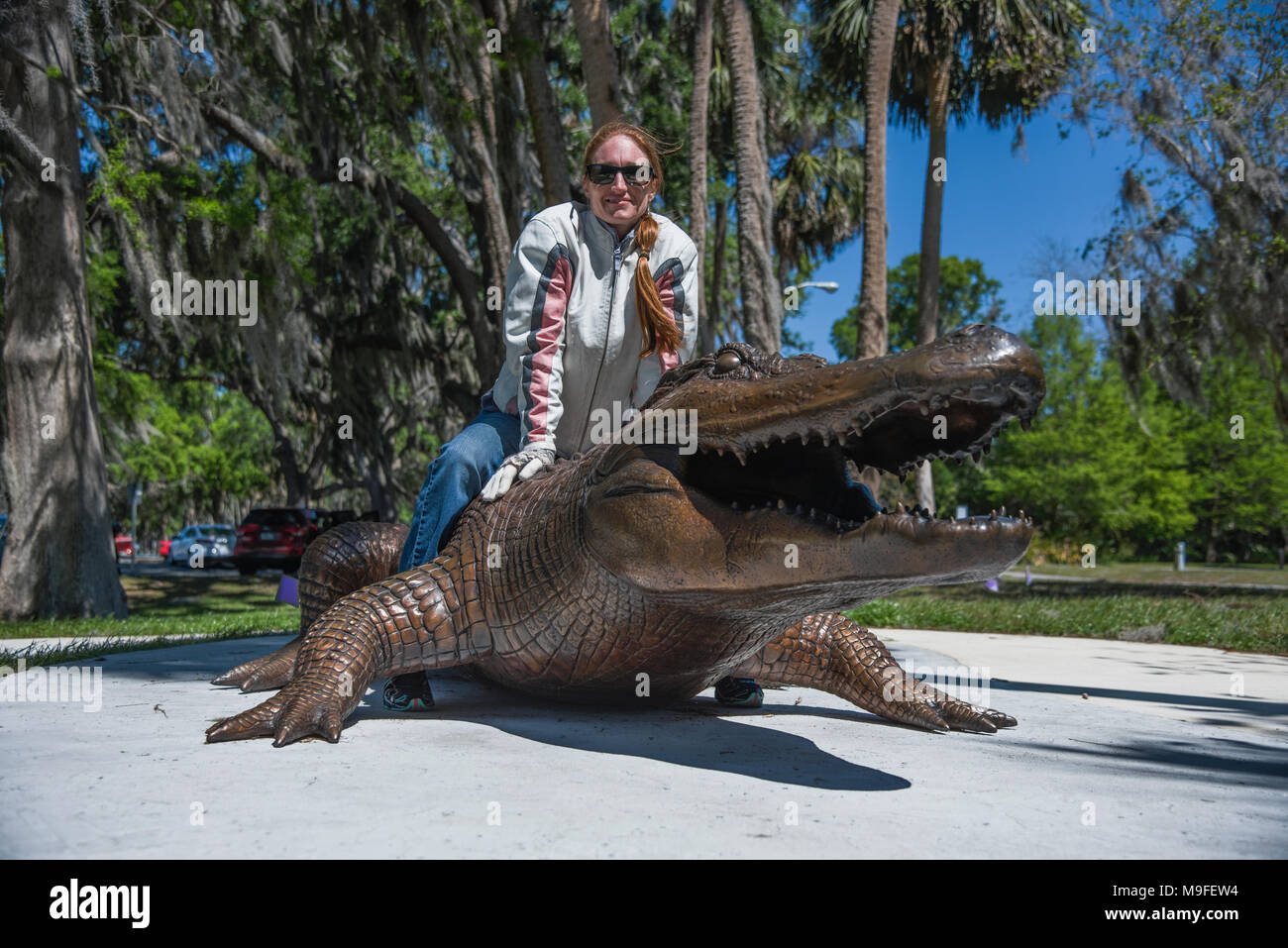 Jolie tête rouge portant des lunettes de soleil fille posant avec un alligator Bronze Statue Banque D'Images