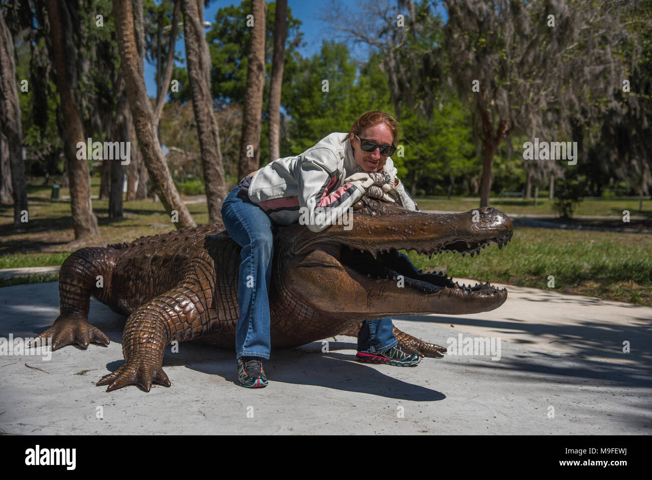 Jolie tête rouge portant des lunettes de soleil fille posant avec un alligator Bronze Statue Banque D'Images