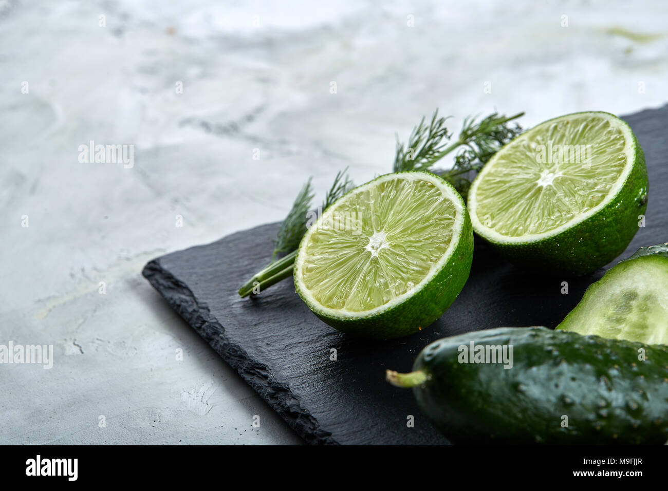 Notion de frais vert laitue, concombre, aneth, citron vert sur noir sur une pierre plate light background, selective focus, vue du dessus, close-up. Banque D'Images