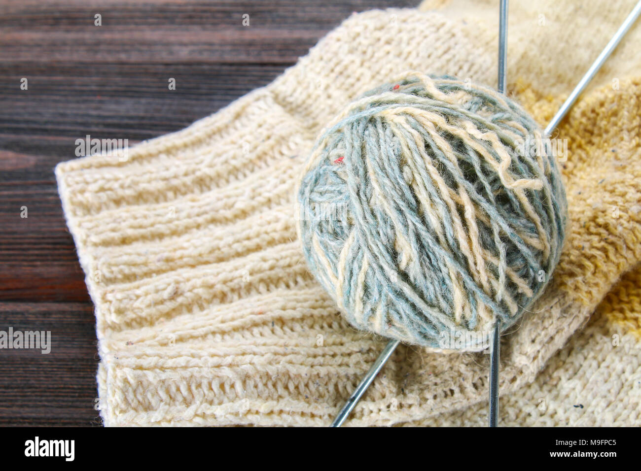 Une balle de laine avec des aiguilles à tricoter chaussettes tricotées et sur une table en bois. La couture Banque D'Images