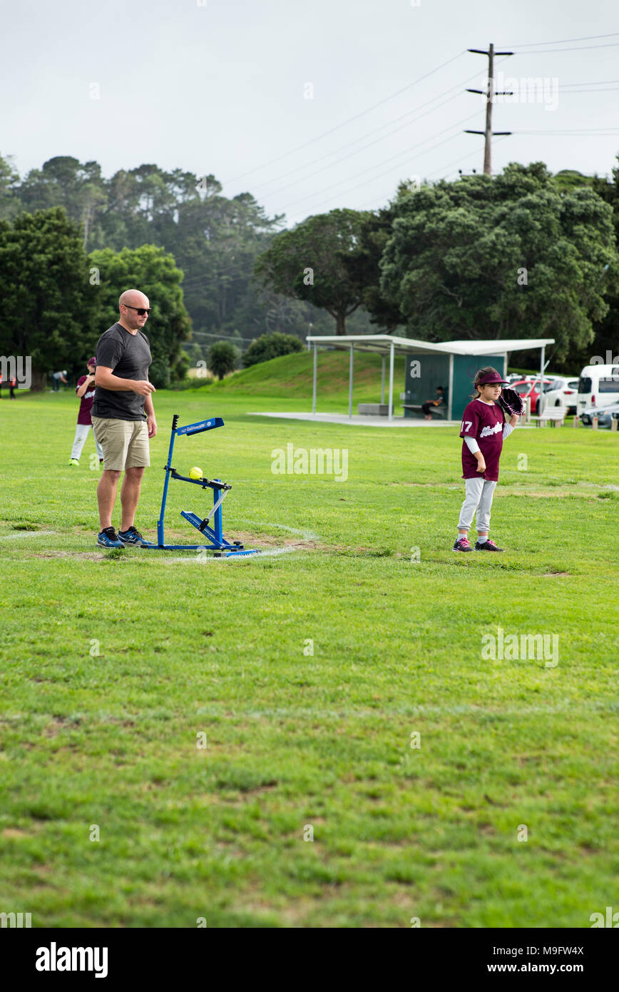 Un adulte utilise un pitching machine pitching suivantes bien qu'avec une action de bras au junior de softball. Banque D'Images