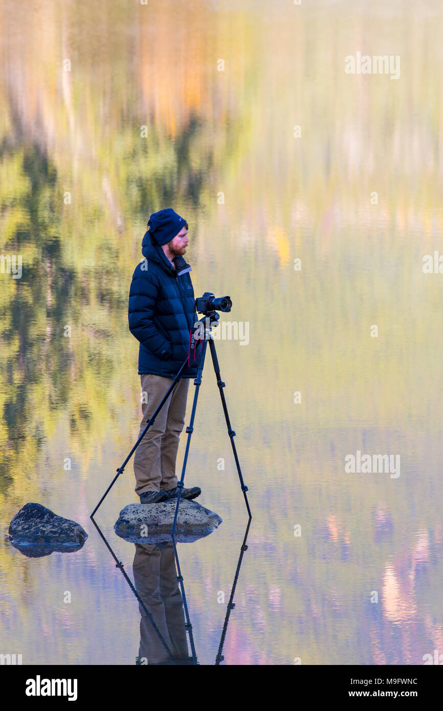Froid 42 641,06237 photographe de paysage en veste chaude patiemment debout sur la roche dans un miroir calme comme le lac, en attente d'instant parfait, réflexions Banque D'Images