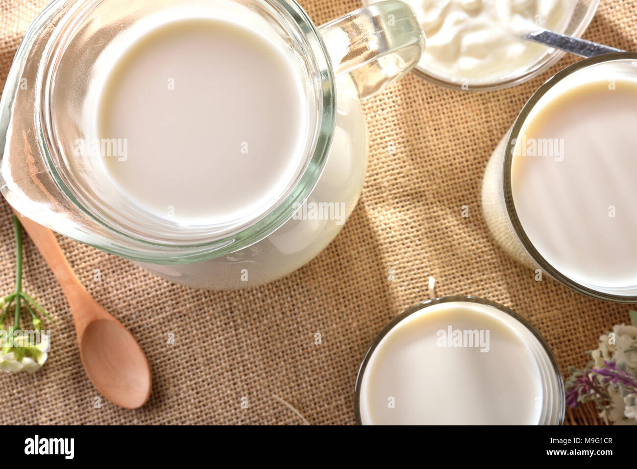 Le lait contenant sur nappe de toile avec fleurs décoratives piscine dans la nature. Composition horizontale. Banque D'Images