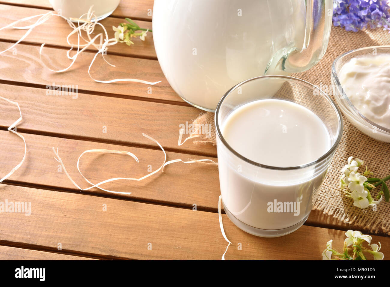 Le lait contenant le tissu de toile cirée sur la table en bois avec fleurs décoratives piscine dans la nature. Composition horizontale. Elevated view Banque D'Images