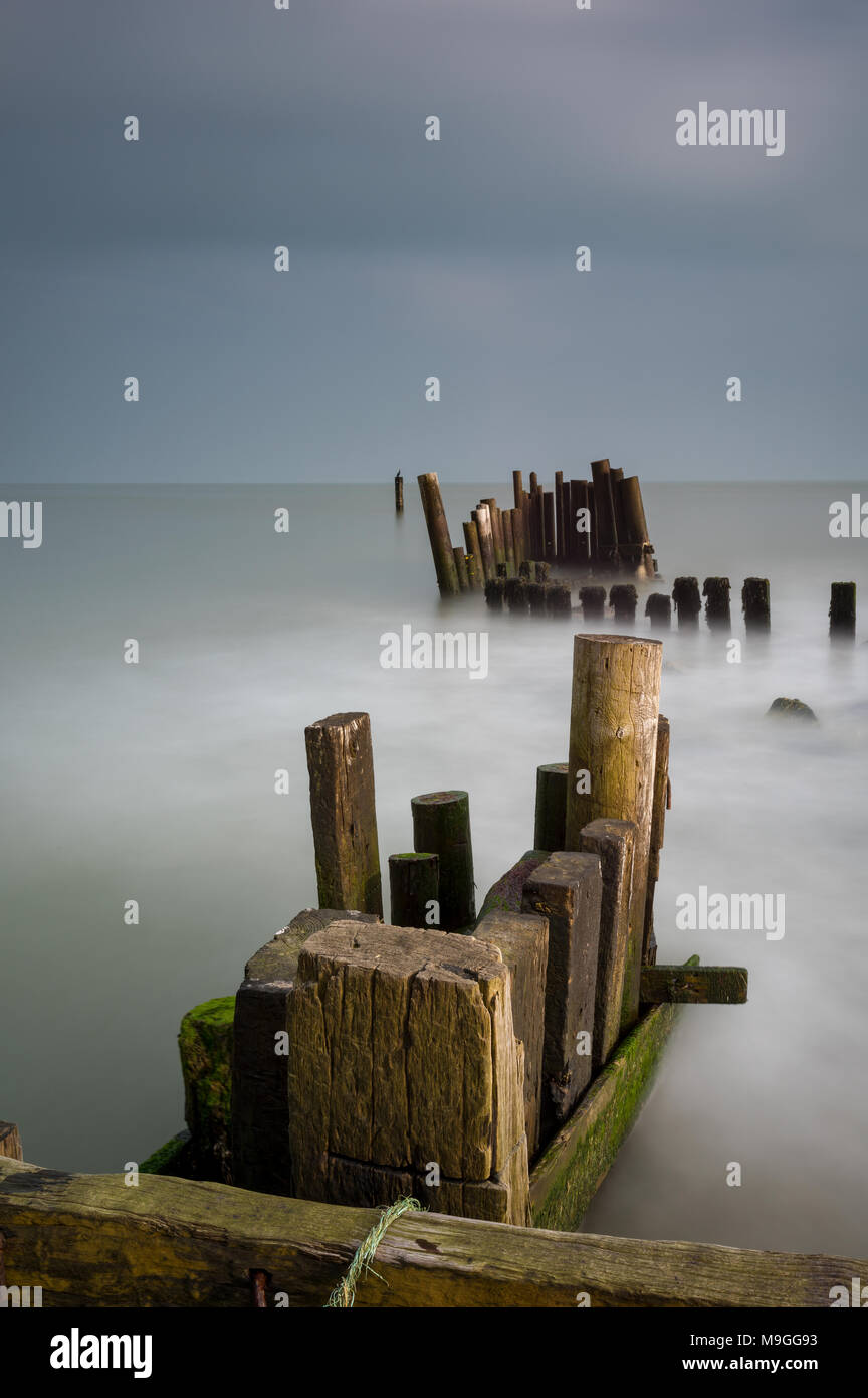 Un générique de l'estran paysage marin côtier sur l'île de Wight avec vieux bois battu météo jetty et piers ou épis et brise-lames. calmante. Banque D'Images