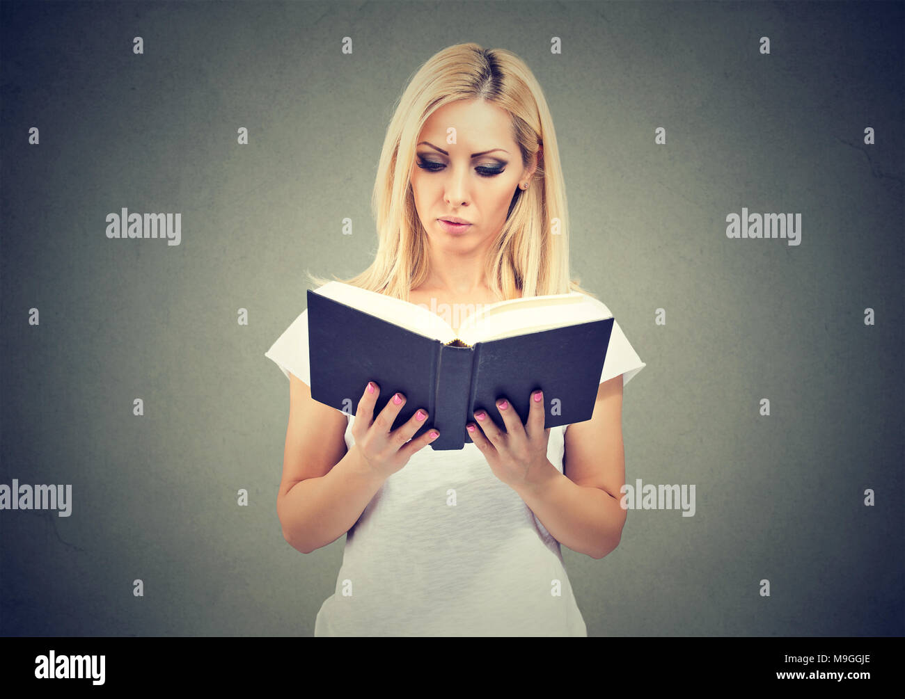 Concentrés casual girl holding et de la lecture livre avec grand intérêt. Banque D'Images