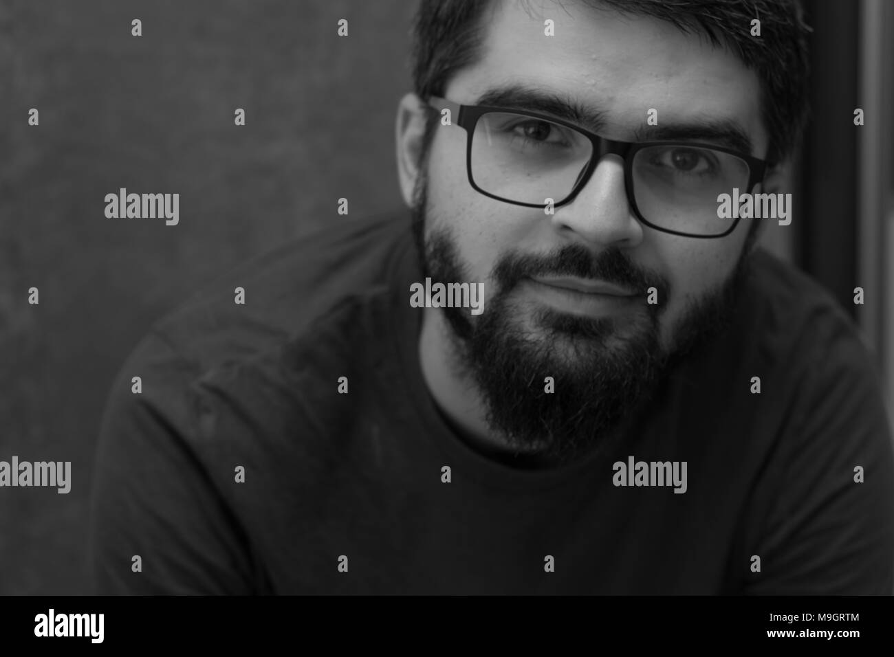 "Je vous vois" - jeune homme avec des lunettes et barbe noir et blanc portrait Banque D'Images
