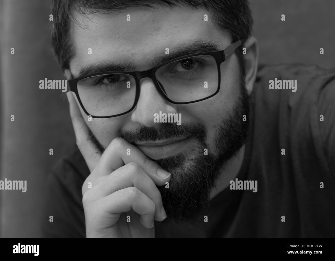 Jeune homme avec des lunettes et barbe noir et blanc portrait Banque D'Images