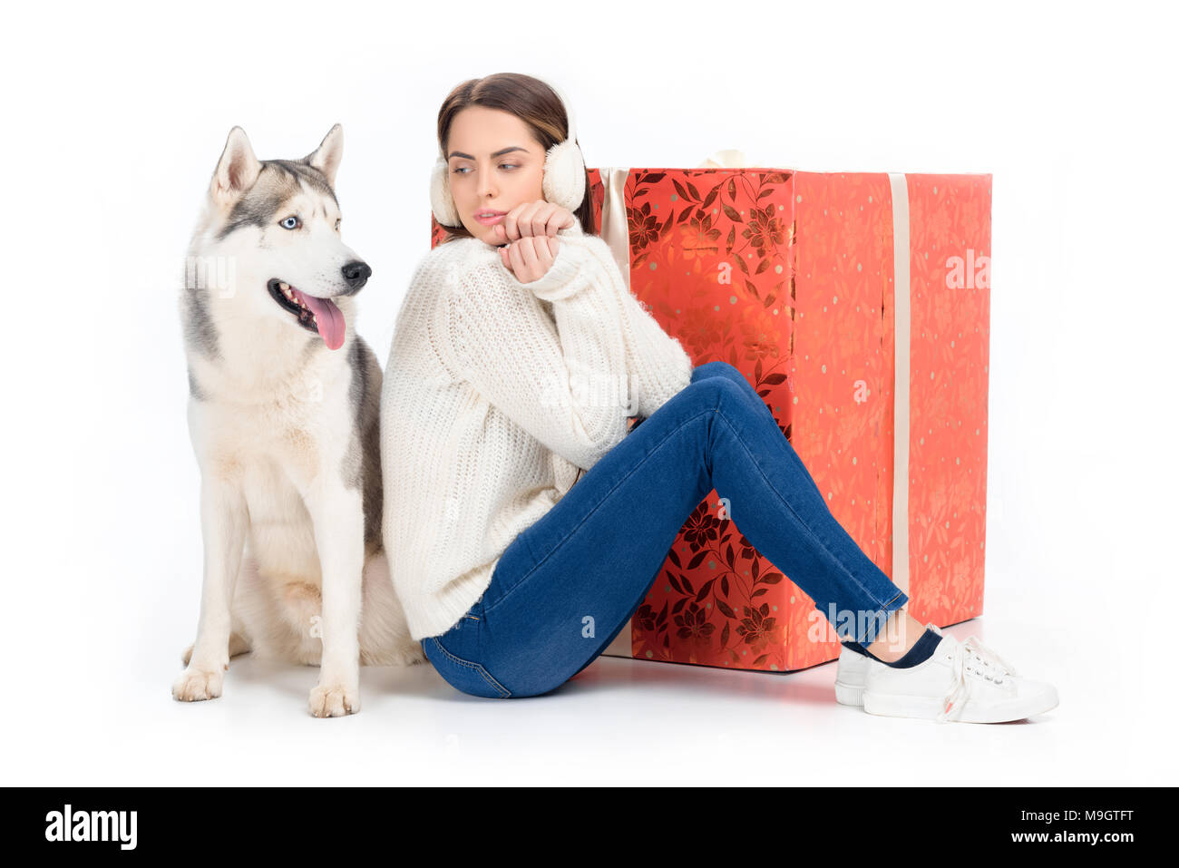 Chien husky et tendre femme en hiver casque antibruit avec de grands cadeaux de Noël derrière, isolated on white Banque D'Images