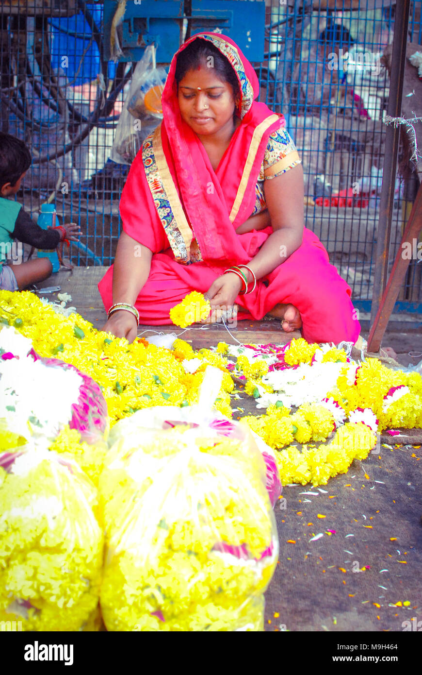 Une femme de la préparation dans une guirlandes fleuriste local rue marché de New Delhi, Inde. Le 29 septembre 2017. Banque D'Images