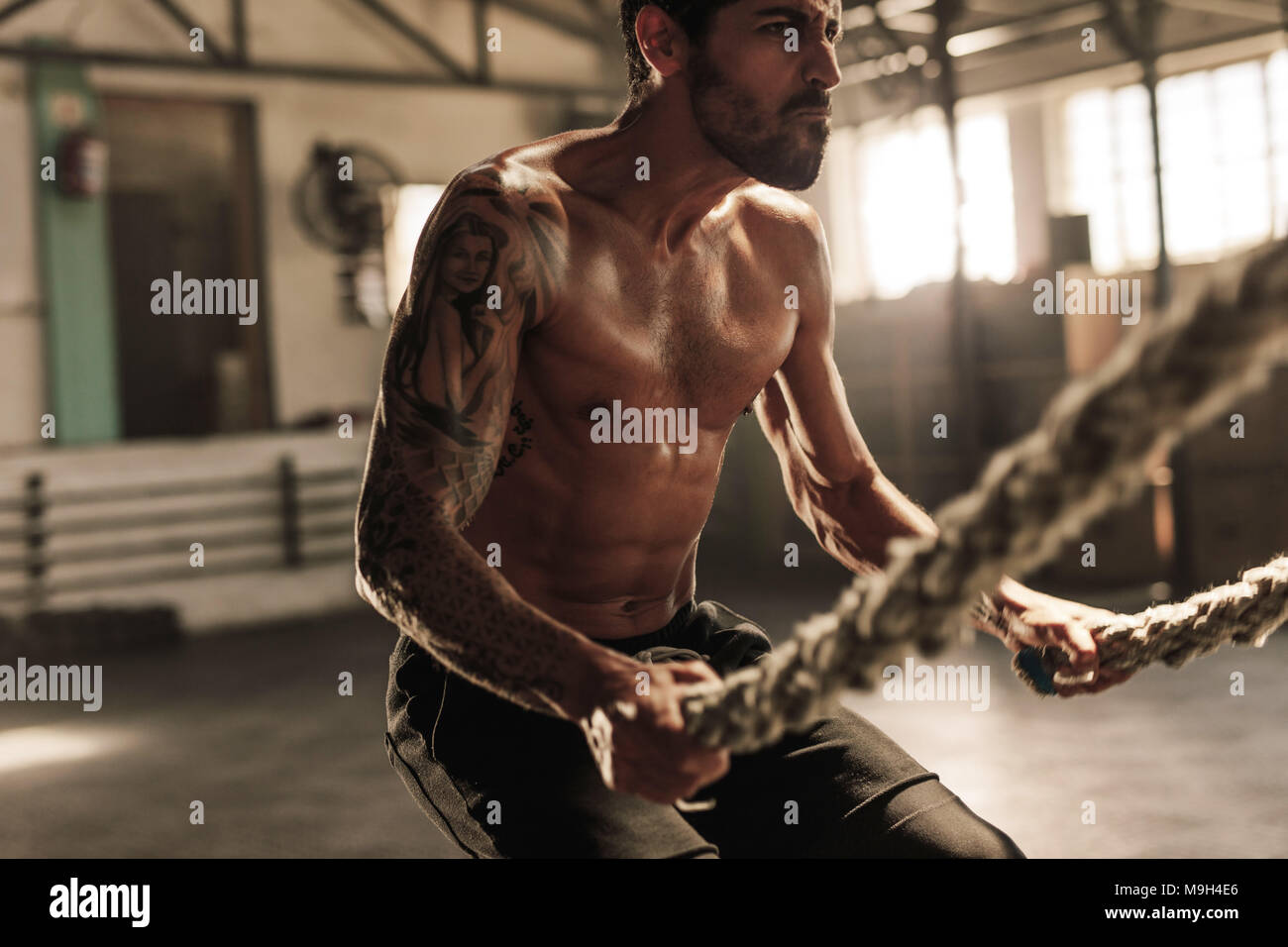 L'exercice de l'homme musclé puissant avec des cordes à la bataille de sport. La formation de force avec des cordes à la bataille de sport. Banque D'Images