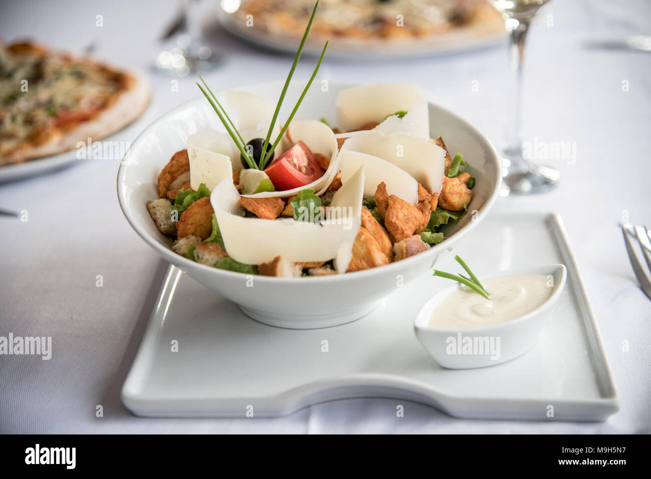 Une superbe salade verte avec du poulet et du fromage. Dans l'arrière-plan, deux pizzas. Tous l'air très élégant et raffiné. Banque D'Images