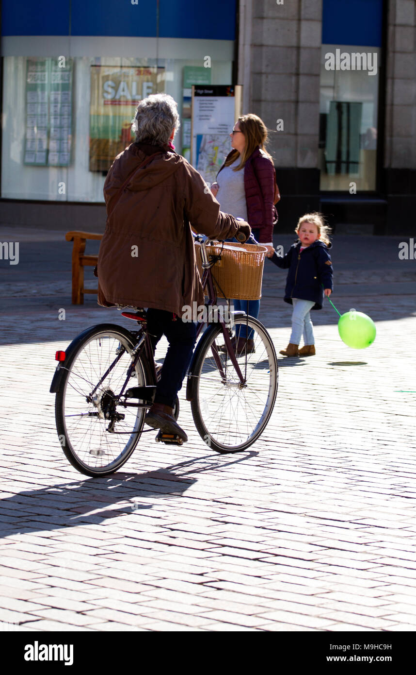 Une femme âgée à vélo sur un ancien style grand-mère vélo le long des rues du centre-ville sur une journée de printemps ensoleillée à Dundee, Royaume-Uni Banque D'Images