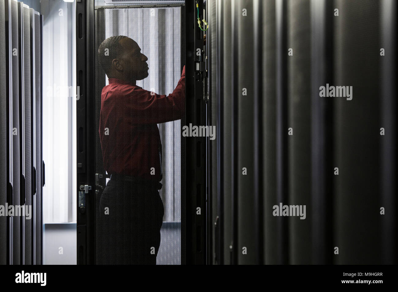 Homme noir technicien travaillant sur des serveurs informatiques dans la batterie de serveurs. Banque D'Images