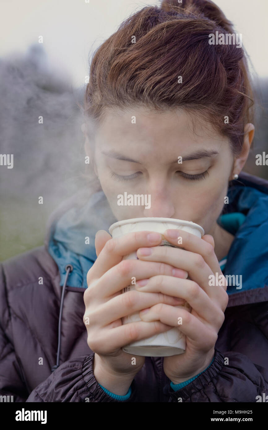 Portrait femme à boire une tasse de café chaud sur une journée d'hiver. Banque D'Images