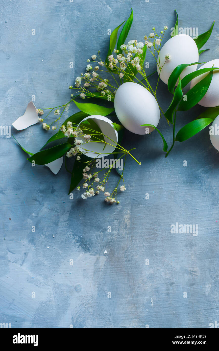 Arrière-plan de Pâques frais généraux avec des œufs blancs, déco feuilles vertes et fleurs de printemps. Concept de cuisine bio. Banque D'Images