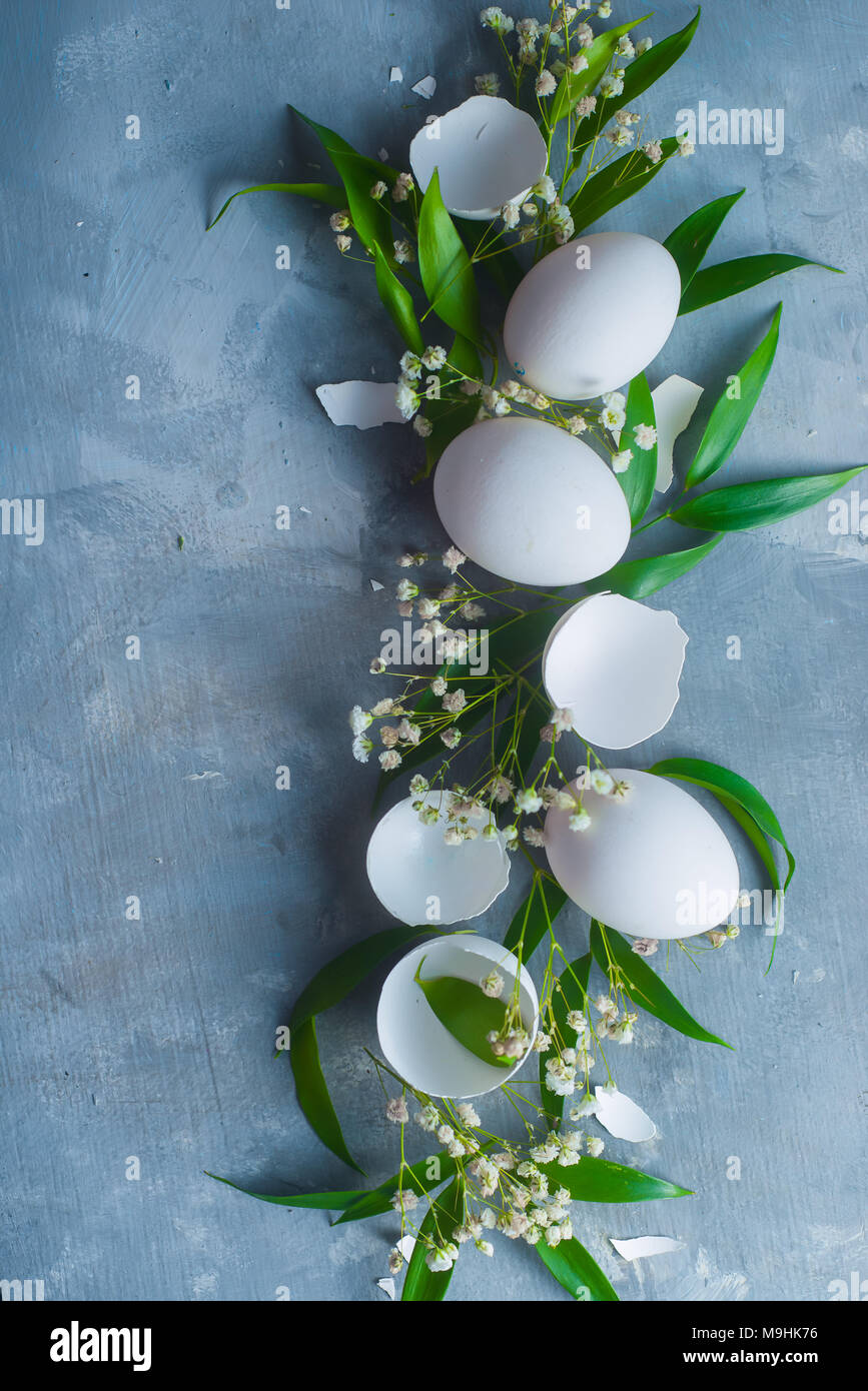 Arrière-plan de Pâques frais généraux avec des œufs blancs, déco feuilles vertes et fleurs de printemps. Concept de cuisine bio. Banque D'Images