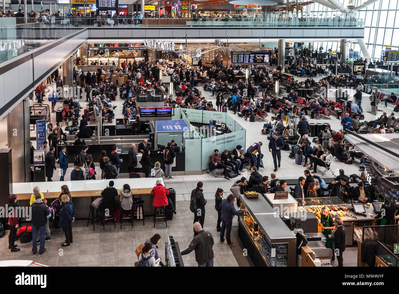 Les passagers qui attendent pour des départs à Heathrow Airport Terminal 5, où de nombreux vols ont été annulés en raison de la neige. BA service client, Starbucks. Banque D'Images