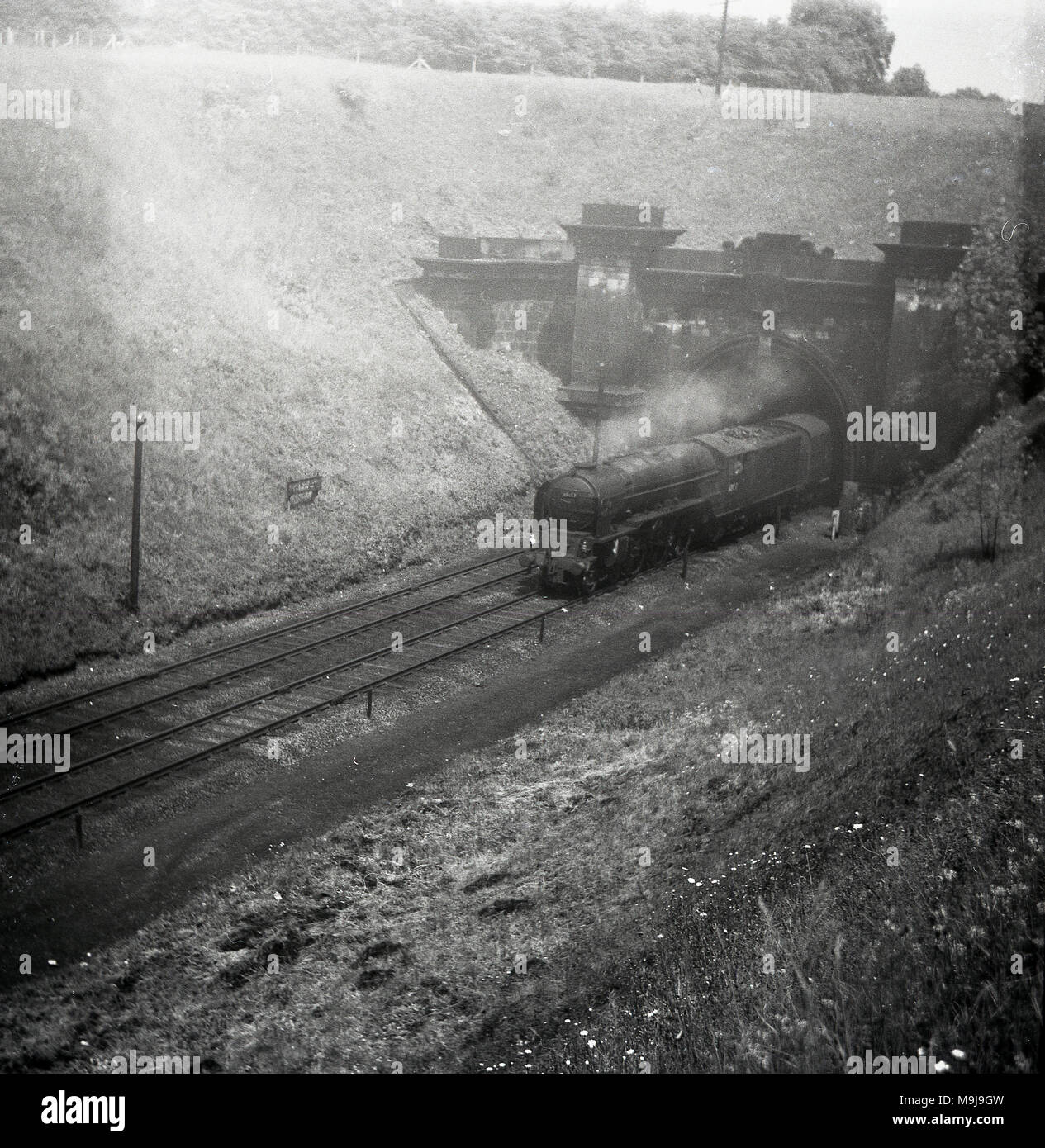 Années 1950, historique, d'une locomotive à vapeur sur une ligne de chemin de fer, qui sortent d'un tunnel, England, UK. Banque D'Images