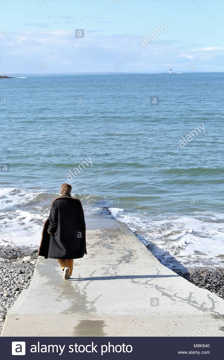 Une belle scène comme une femme marche dans la cale vers la rive à Rosses Point sur la côte ouest de l'Irlande. Credit : reallifephotos / Alamy Banque D'Images