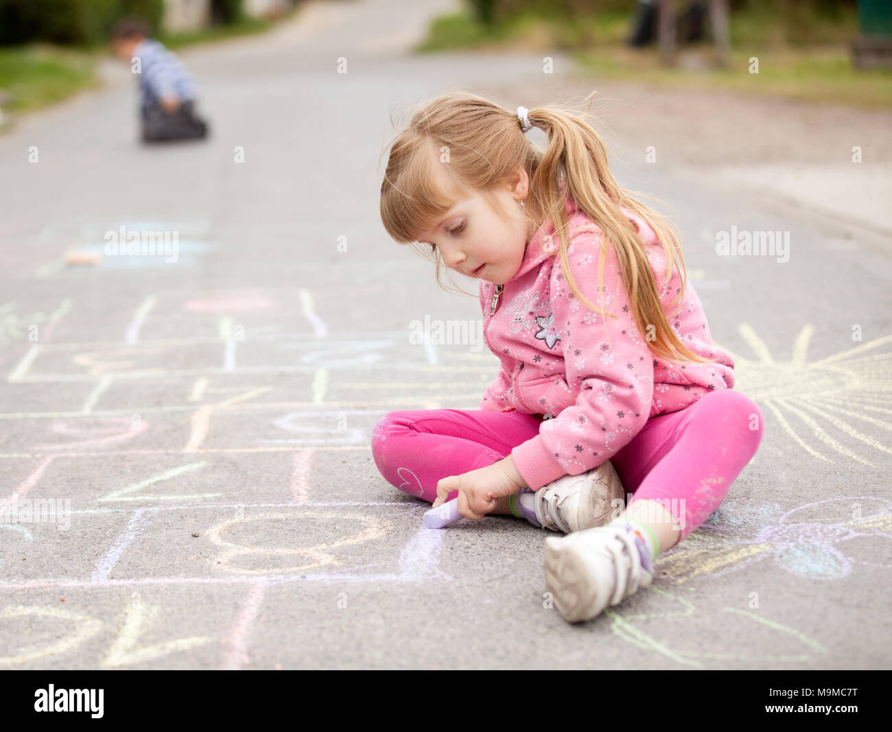 Petite fille dessin à la craie à l'extérieur Banque D'Images