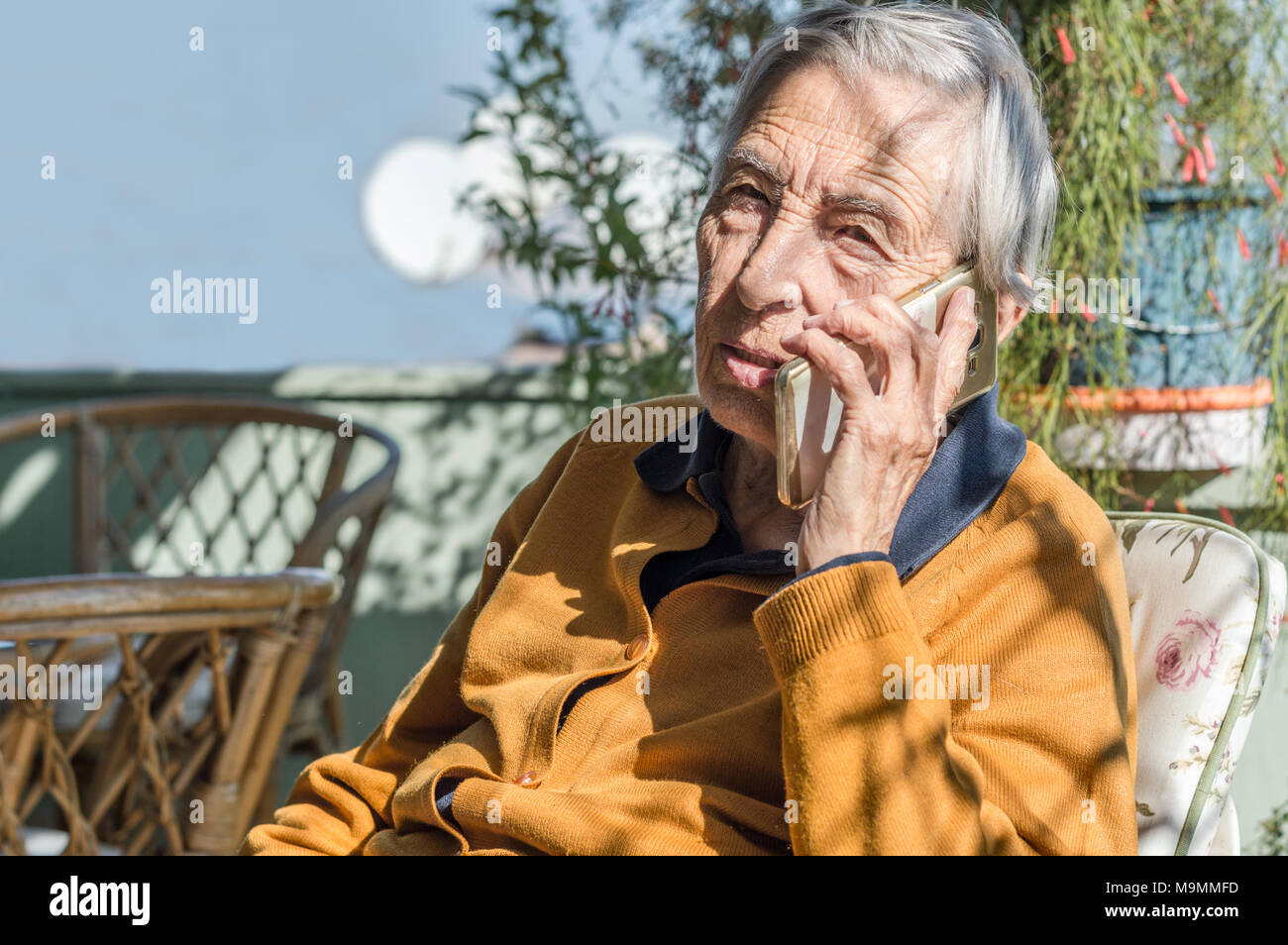 Vieille Femme assis sur le balcon à parler sur son téléphone portable. Banque D'Images